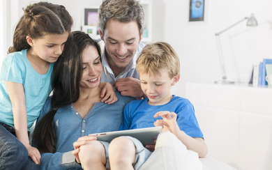 Bild einer Familie, die auf ein Tablet schaut.