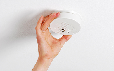 Frauenhand bei einem Rauchwarnmelder